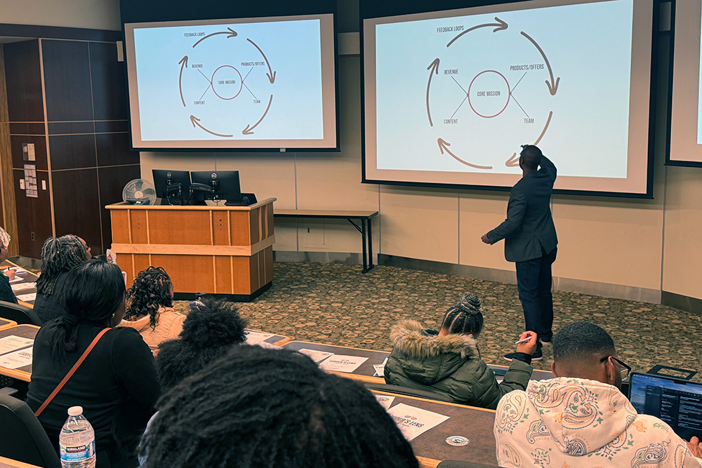 a presenter pointing to a graphic on a project during a Be BLAC Foundation Spring Expo event